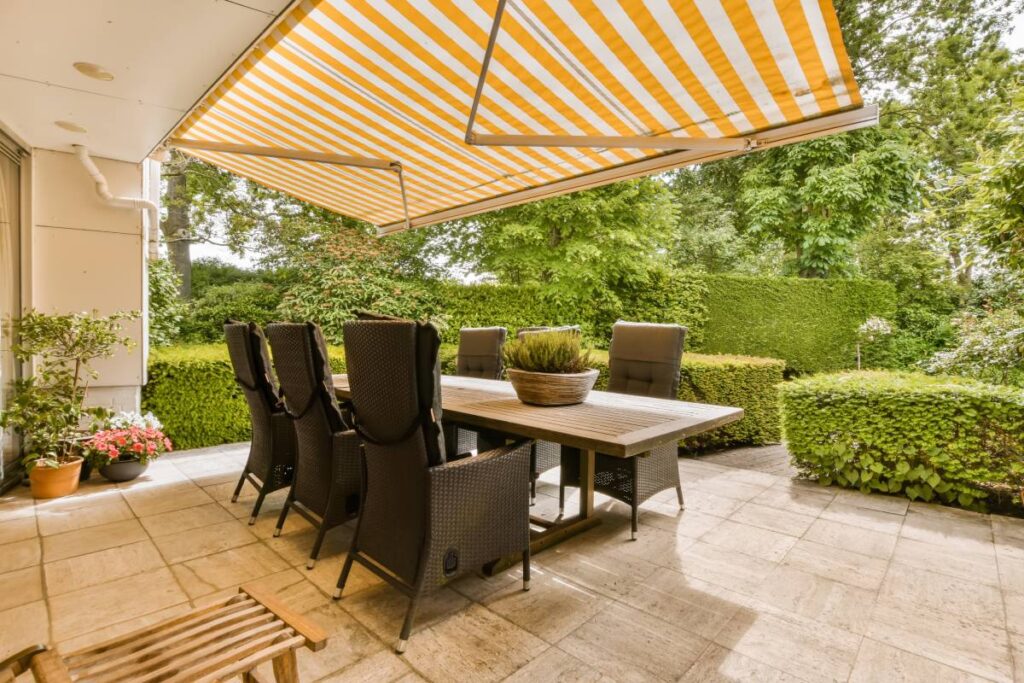 An outdoor oasis with a yellow and white striped exterior awning over an outdoor dining set near Kerrville, TX