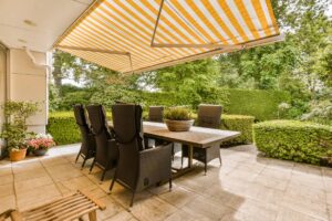 An outdoor oasis with a yellow and white striped exterior awning over an outdoor dining set near Kerrville, TX