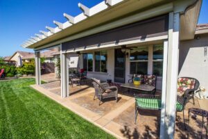 A residential home’s patio with outdoor roller shades, partially open, and assorted outdoor furniture near Kerrville, TX