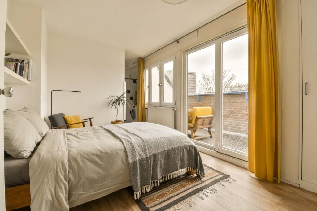 A cozy guest bedroom with yellow custom drapery on windows and a sliding door at Kerrville Window Fashionsnear Kerrville, TX