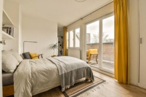 A cozy guest bedroom with yellow custom drapery on windows and a sliding door at Kerrville Window Fashionsnear Kerrville, TX