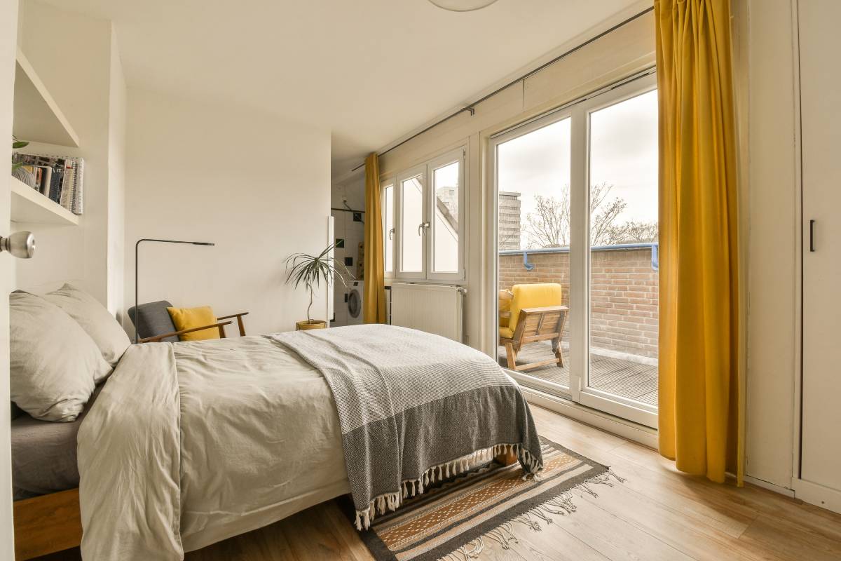 A cozy guest bedroom with yellow custom drapery on windows and a sliding door at Kerrville Window Fashionsnear Kerrville, TX
